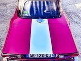 photograph of a pink and white car parked in a parking lot