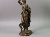 an antique bronze statue of a woman holding a dog