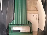 a green trash can with some papers and a cell phone in it