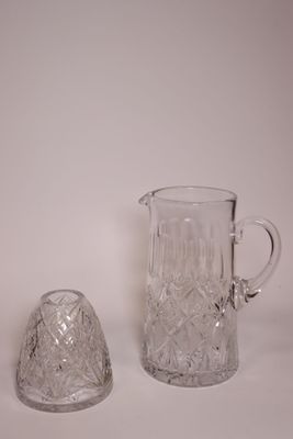 un pichet en verre et une cloche en verre posés sur une surface blanche