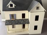 une maison de poupées blanche avec un toit noir et deux fenêtres