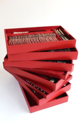stack of red boxes with silverware in them on a white surface