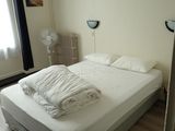 un lit recouvert de draps blancs dans une petite chambre