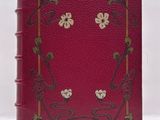 an old red book with flowers and vines on the cover