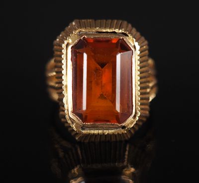 un gros plan d'une bague ornée d'une pierre orange sur un fond noir