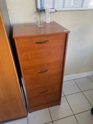 une commode en bois à trois tiroirs placée près d'une fenêtre