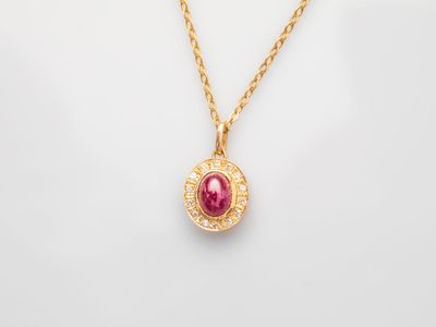 a gold necklace with a ruby stone and diamonds