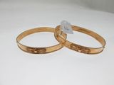 two gold tone bang bracelets with engraved designs on them