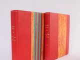 two red books sitting next to each other on a white surface
