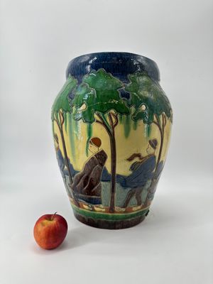 un vase orné d'une peinture, avec une pomme à côté