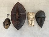 trois masques en bois accrochés au mur les uns à côté des autres