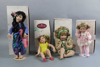 three boxed dolls of children sitting next to each other on a table