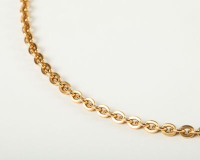 a close up of a gold chain necklace on a white surface