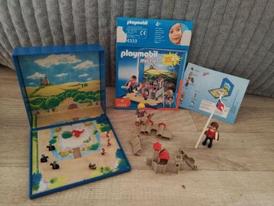 une boîte de Playmobil posée par terre à côté d'autres jouets
