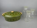 une cocotte verte avec un couvercle en bois et un service de verres