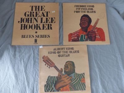 three posters of the great john lee hooker blues series on a bed
