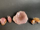 three pieces of pink quartz on a black surface with a goldfish