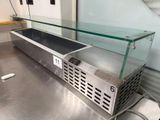 un plan de travail en acier inoxydable surmonté d'une vitrine en verre