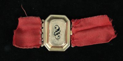 a small silver watch with a red band on a black surface