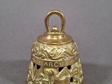 an old brass bell on a gray surface with a bird on it
