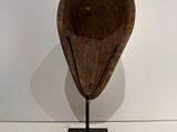 sculpture of a wooden bowl on a metal stand against a white wall