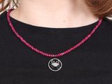 the woman is wearing a black shirt and a red beaded necklace