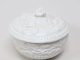 un bol blanc avec un couvercle posé sur une table blanche