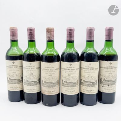 six bouteilles de vin sont alignées sur une surface blanche