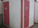 a small red and white building next to a trash can