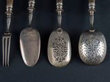 four spoons and a fork are lined up on a black surface