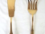 two gold forks and a knife on a white cloth