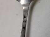 a silver spoon with a handle sitting on a white surface