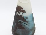 a small vase with a tree on it on a white surface