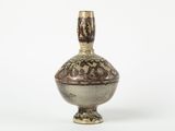 un petit vase posé sur une surface blanche