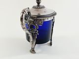a blue glass jar with a silver lid on a stand