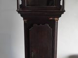 une horloge de parquet posée par terre à côté d'une boîte