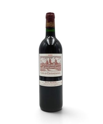 a bottle of red wine sitting on top of a white table