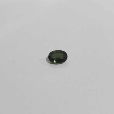 a green tourmaline gems on a white surface