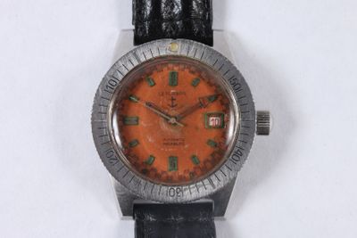 wrist watch with orange dial and black leather strap on white surface