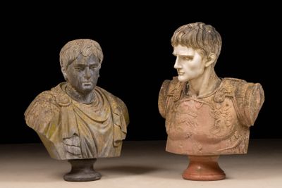 two busts of roman men on pedestals against a black background