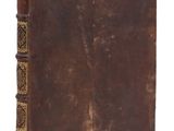 un vieux livre à la couverture brune posé sur une surface blanche