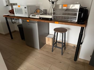une petite cuisine équipée d'un micro-ondes, d'un réfrigérateur et d'un tabouret de bar