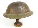 an old rusty helmet on a wooden base on a white background