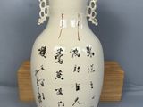 a white vase with asian writing on it sitting on a wooden stand