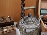 a silver teapot sitting on a table next to other items