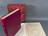 un livre rouge ouvert posé sur une table, à côté d'un livre rouge