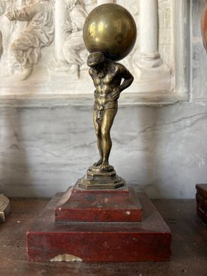 a statue of a boy holding a ball on his head