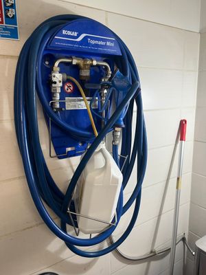 un tuyau bleu fixé au mur à côté des toilettes