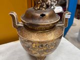 brass teapot with a lion on top of it on a table