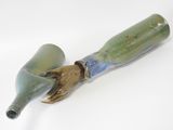 a green glass bottle with a blue handle on a white surface